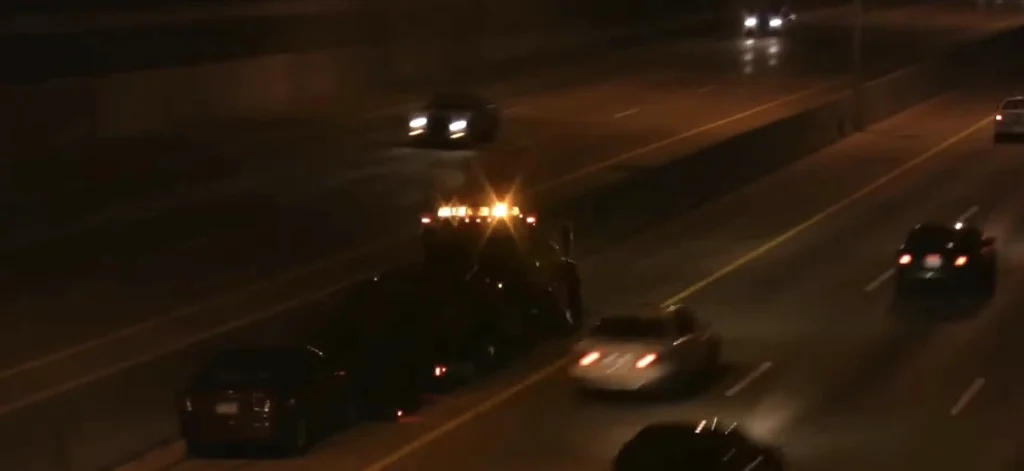 24 Hour Towing 2 tow truck driving down highway at night